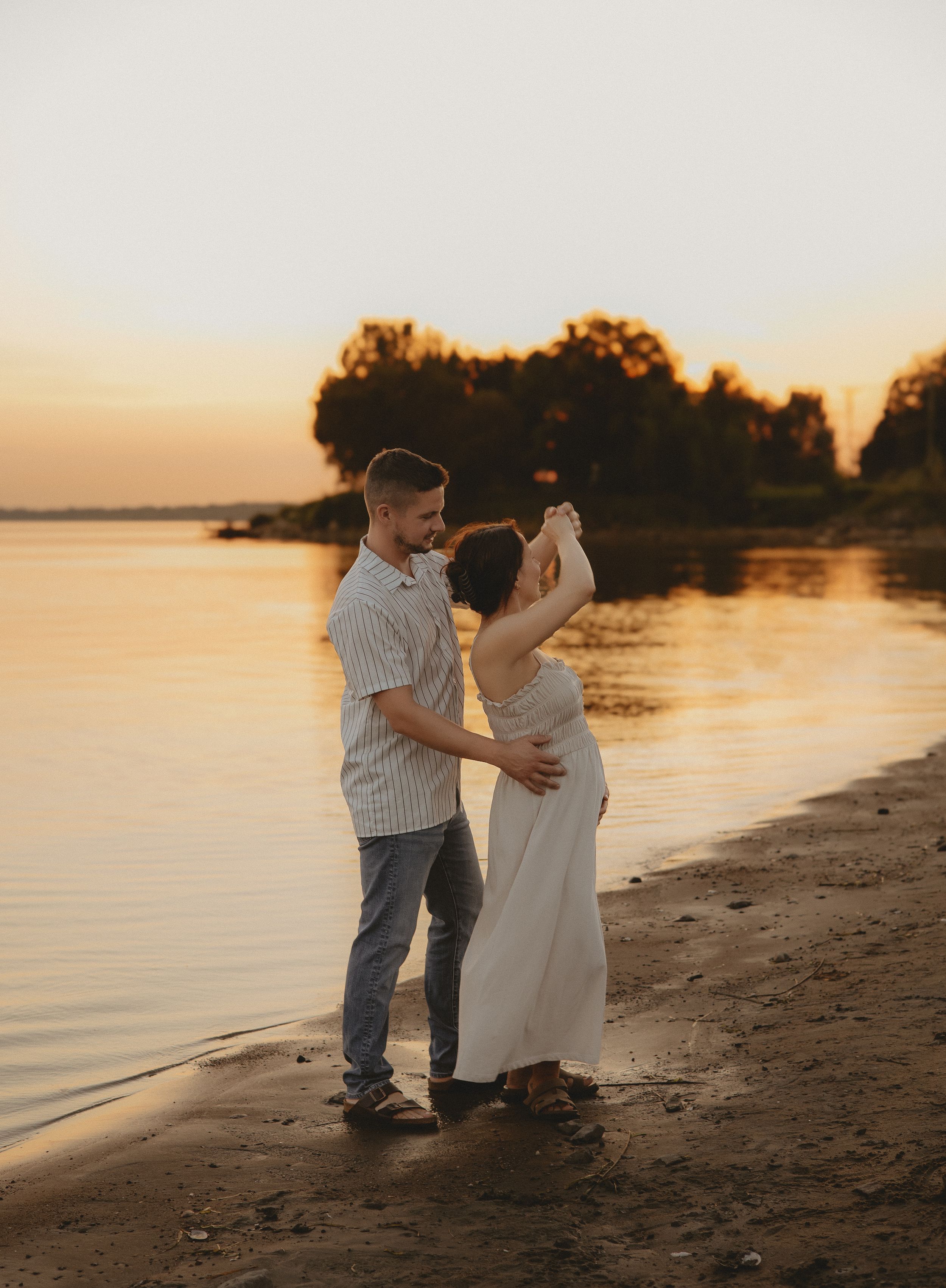 A couple shares an intimate moment on the beach during golden hour.