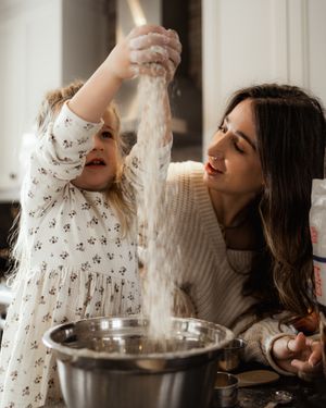A joyful baking scene with flour being sprinkled in a sunny kitchen.