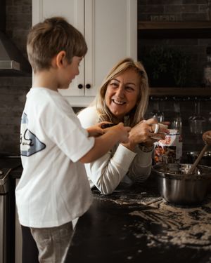 A joyful baking scene shows shared laughter in a modern kitchen with white cabinets.