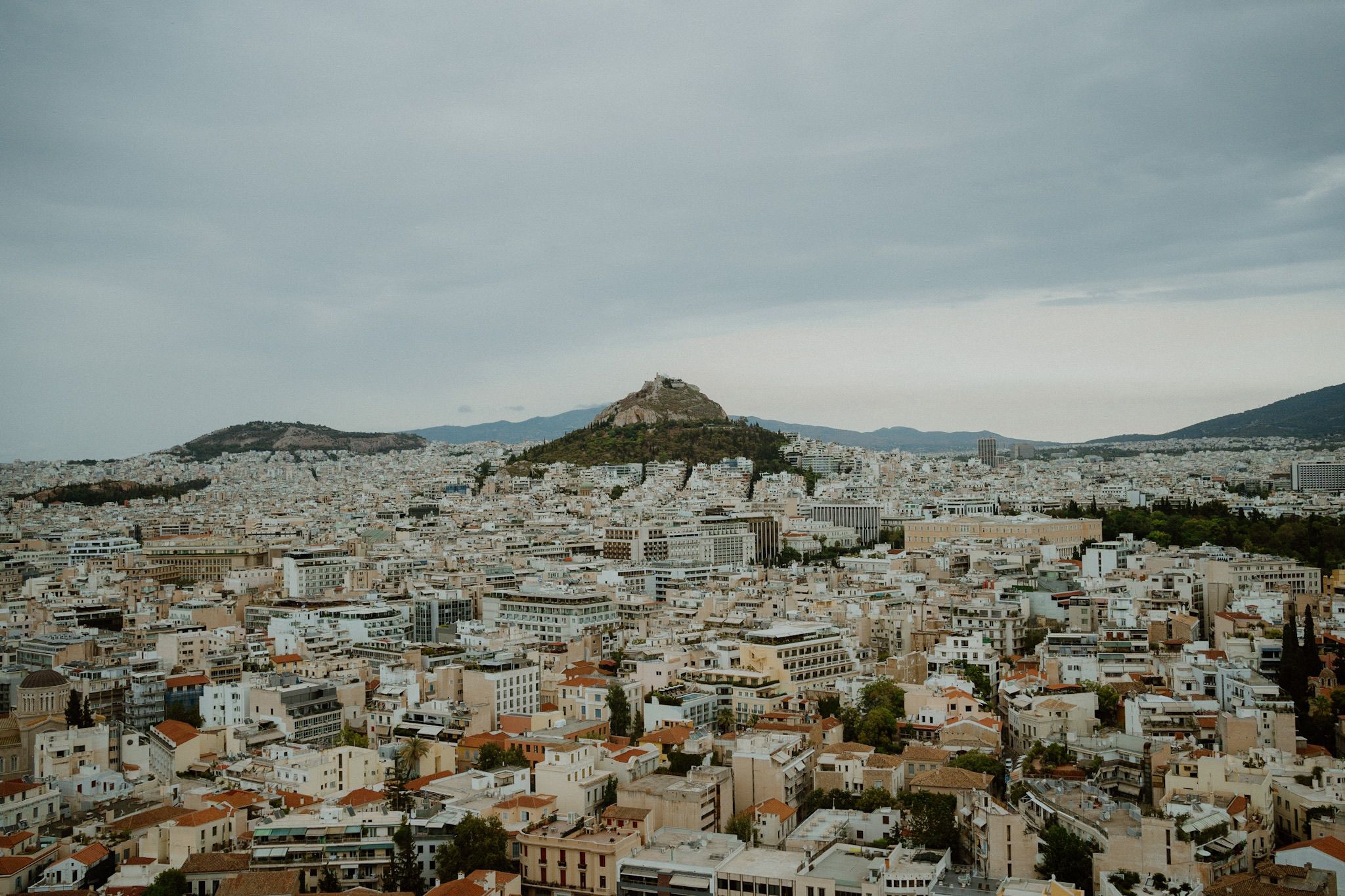 Aerial view of Athens cityscape with Mount Lycabettus rising above densely packed buildings and houses.