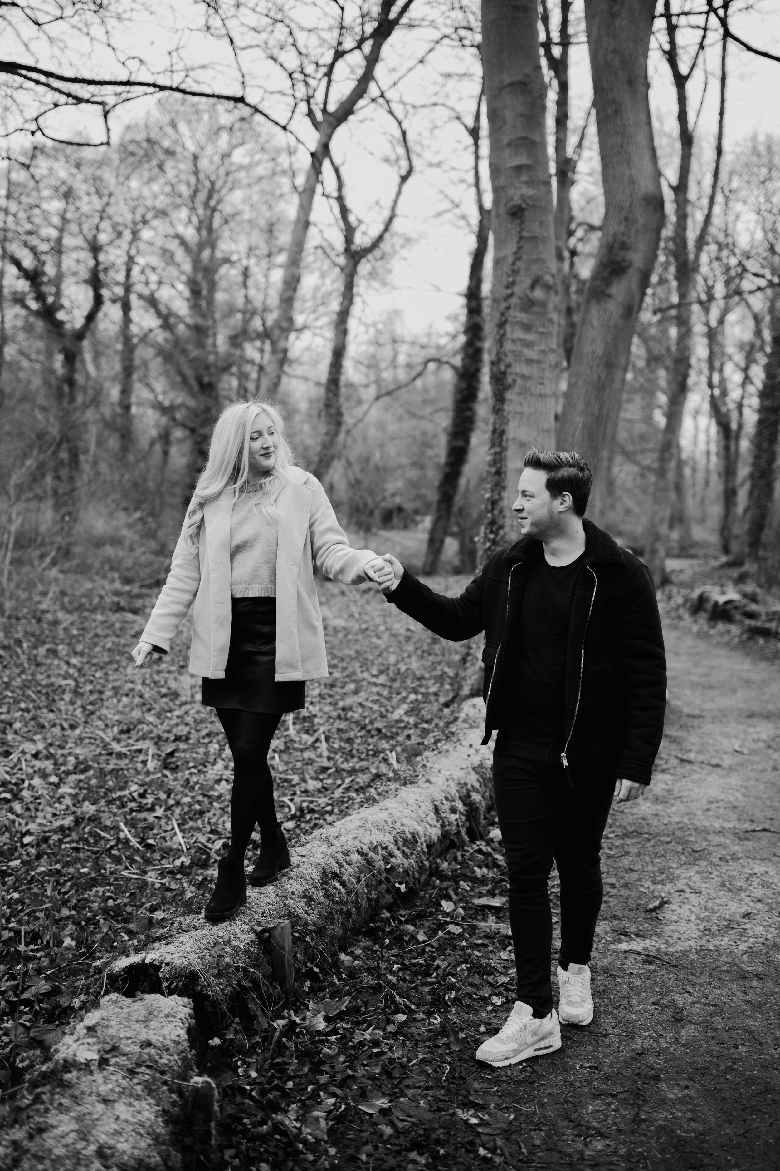 A black and white photo of a couple walking along a wooded path in winter.