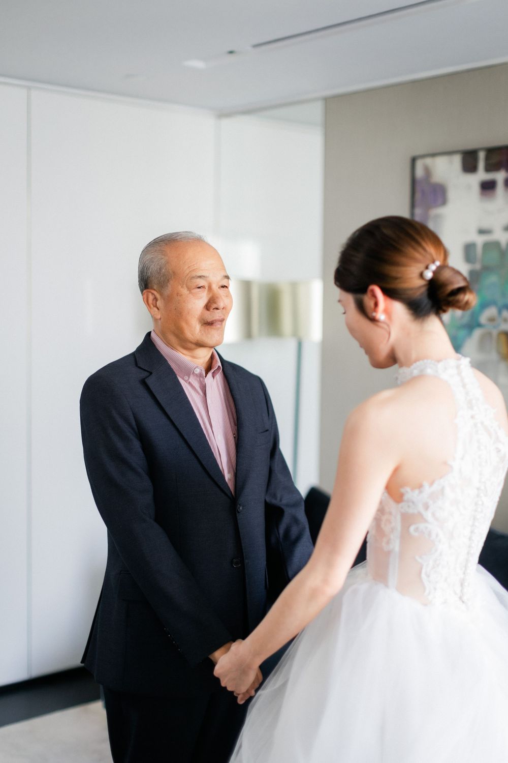 Father holds bride's hands during emotional first look moment before wedding ceremony.