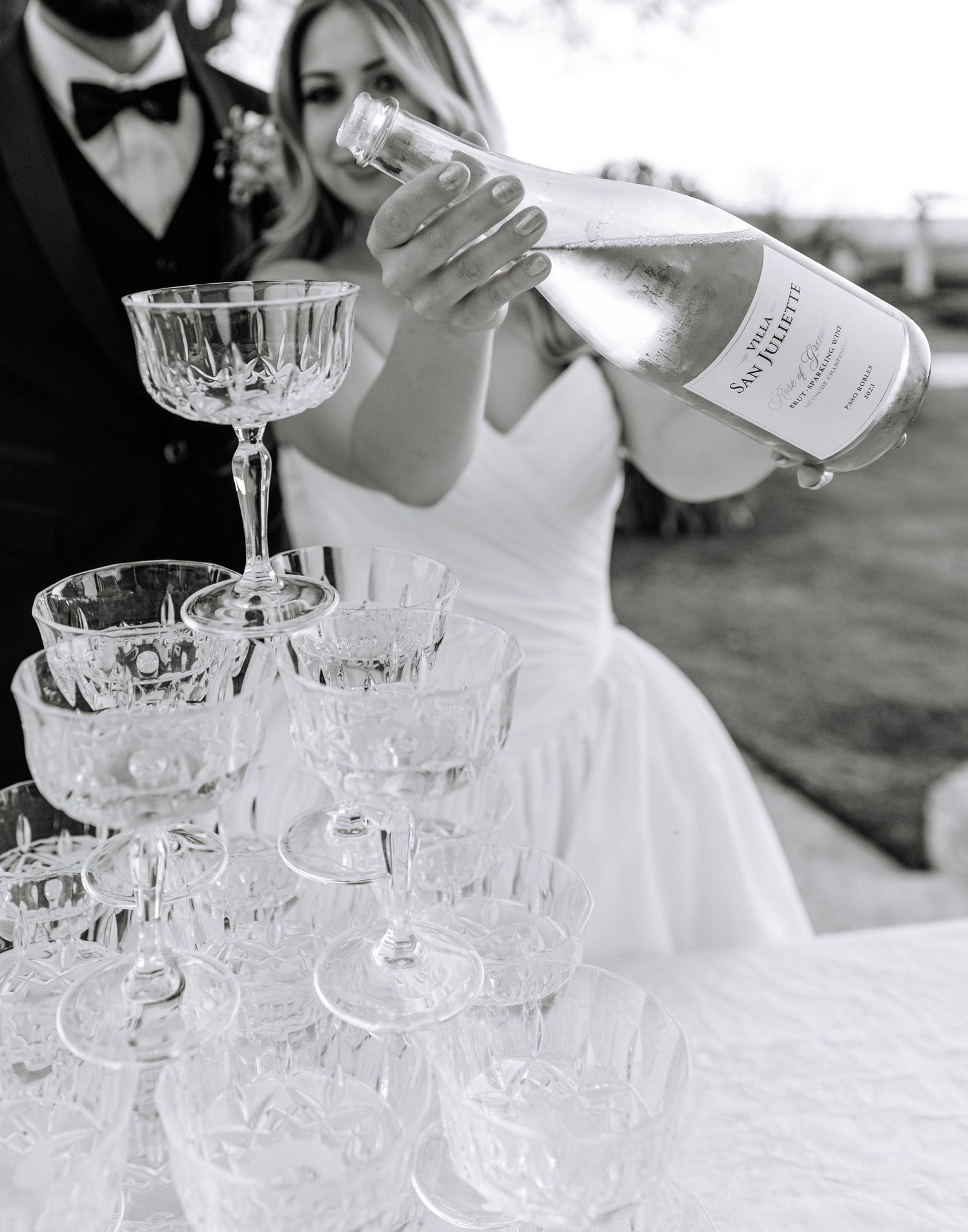 Champagne being poured into an elegant tower of crystal glasses at a wedding reception.