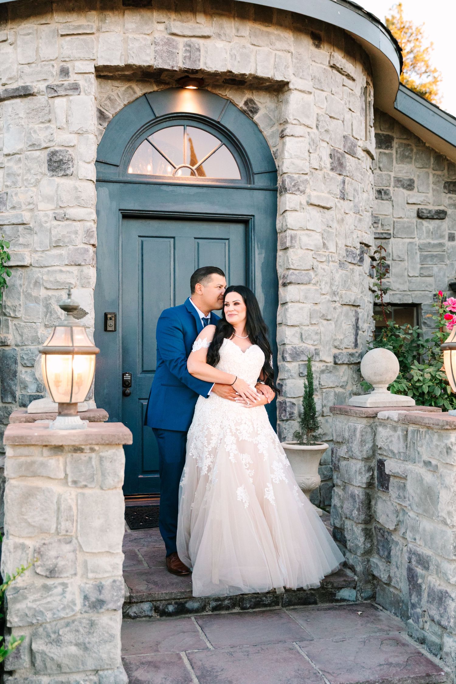 Stone building entrance with blue arched doors serves as romantic backdrop at golden hour.
