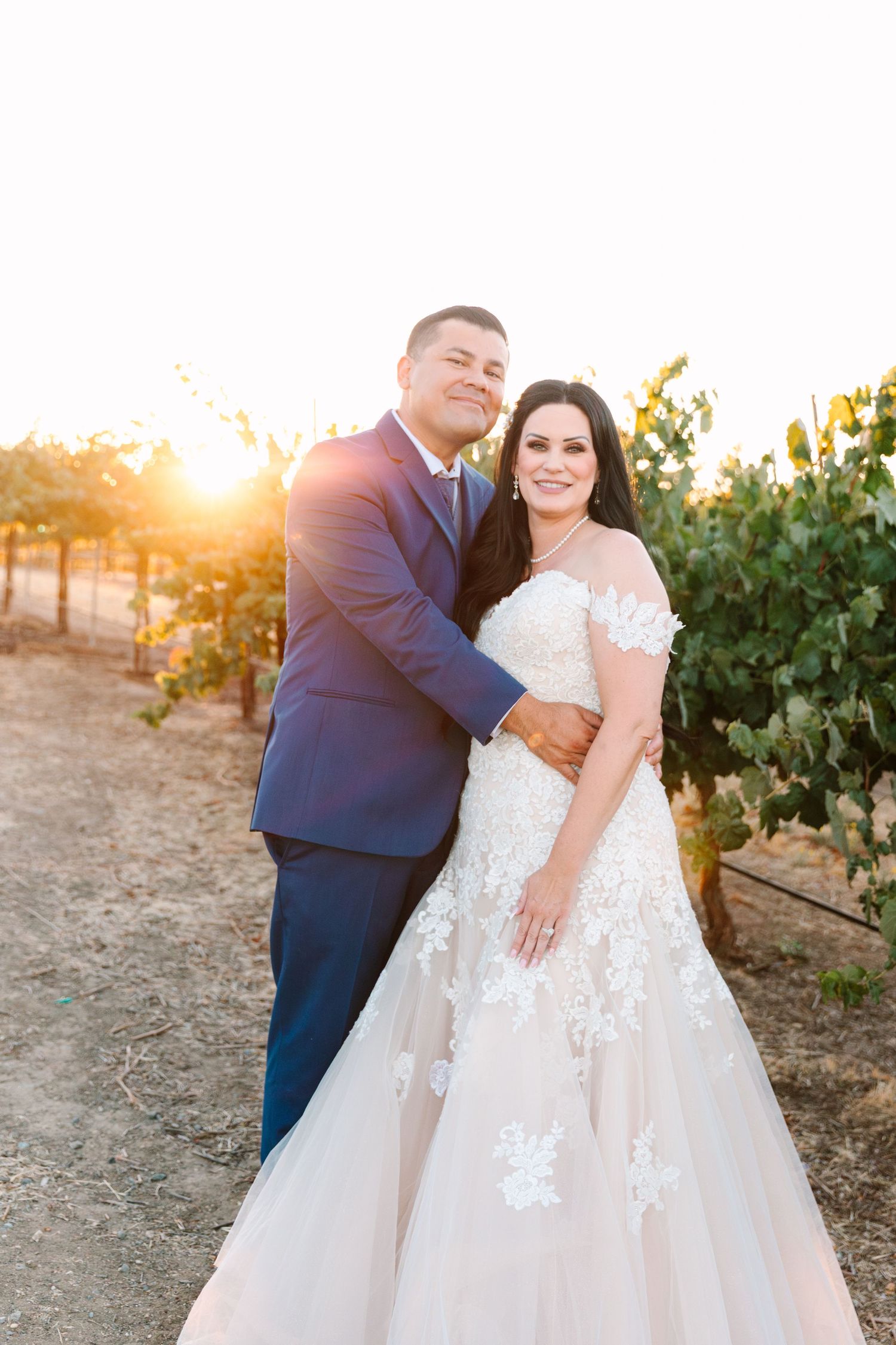 Sunset vineyard photoshoot among grapevines with soft golden light filtering through.