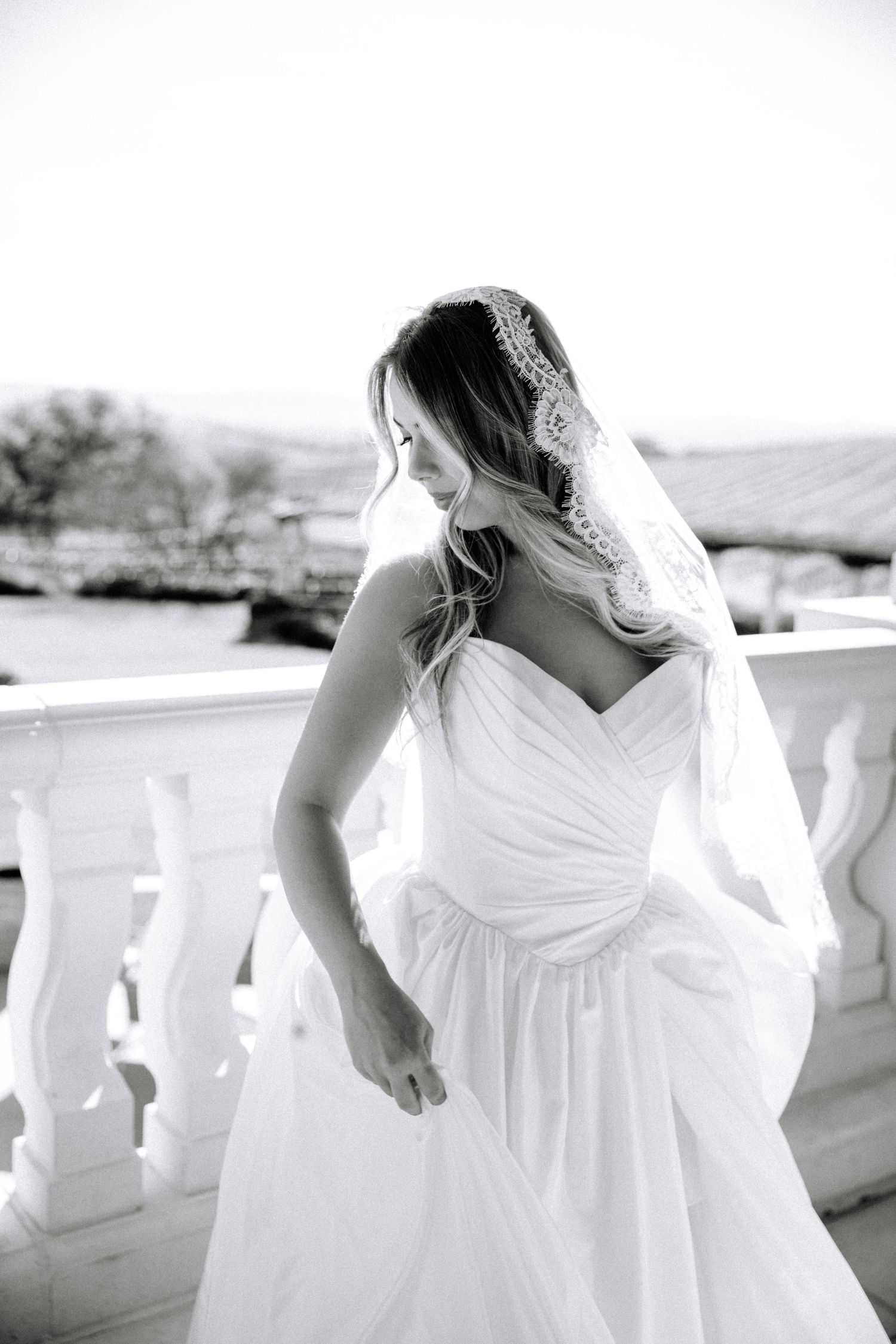 Black and white photo showing the flowing details of a white wedding dress with a sweetheart neckline and ruched bodice.