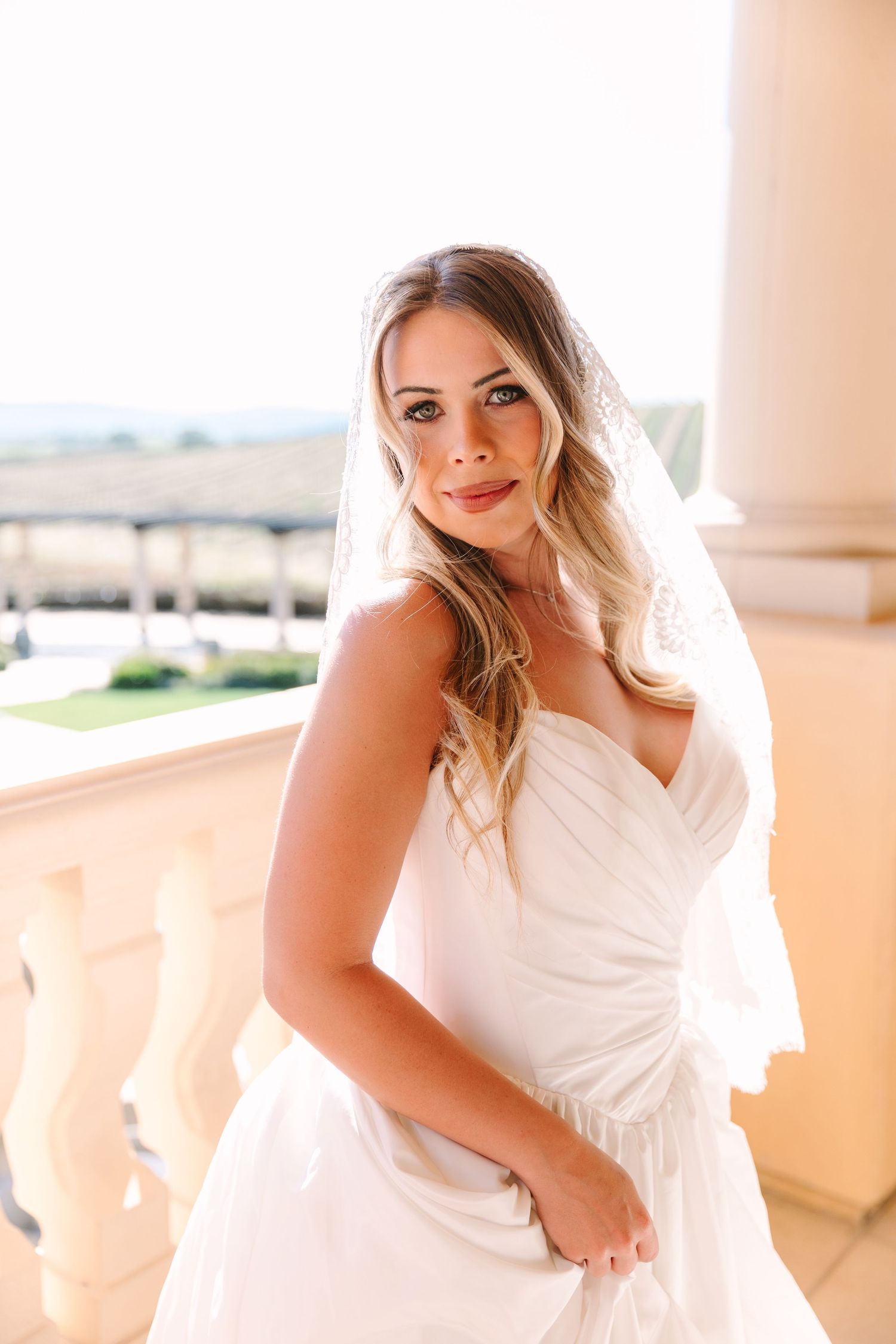 An elegant bridal portrait on a Mediterranean-style balcony with scenic views.