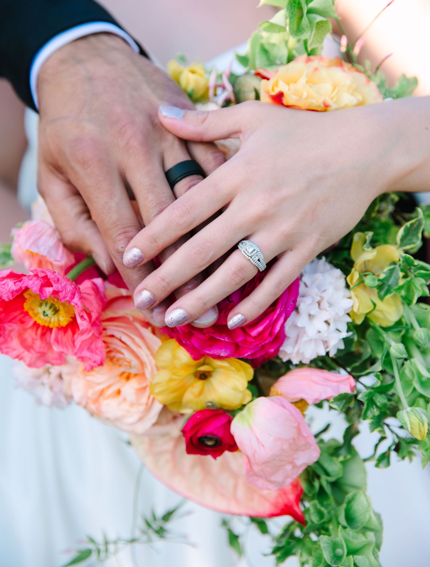 Colorful floral arrangement with pink and peach blooms alongside green foliage on a white surface.