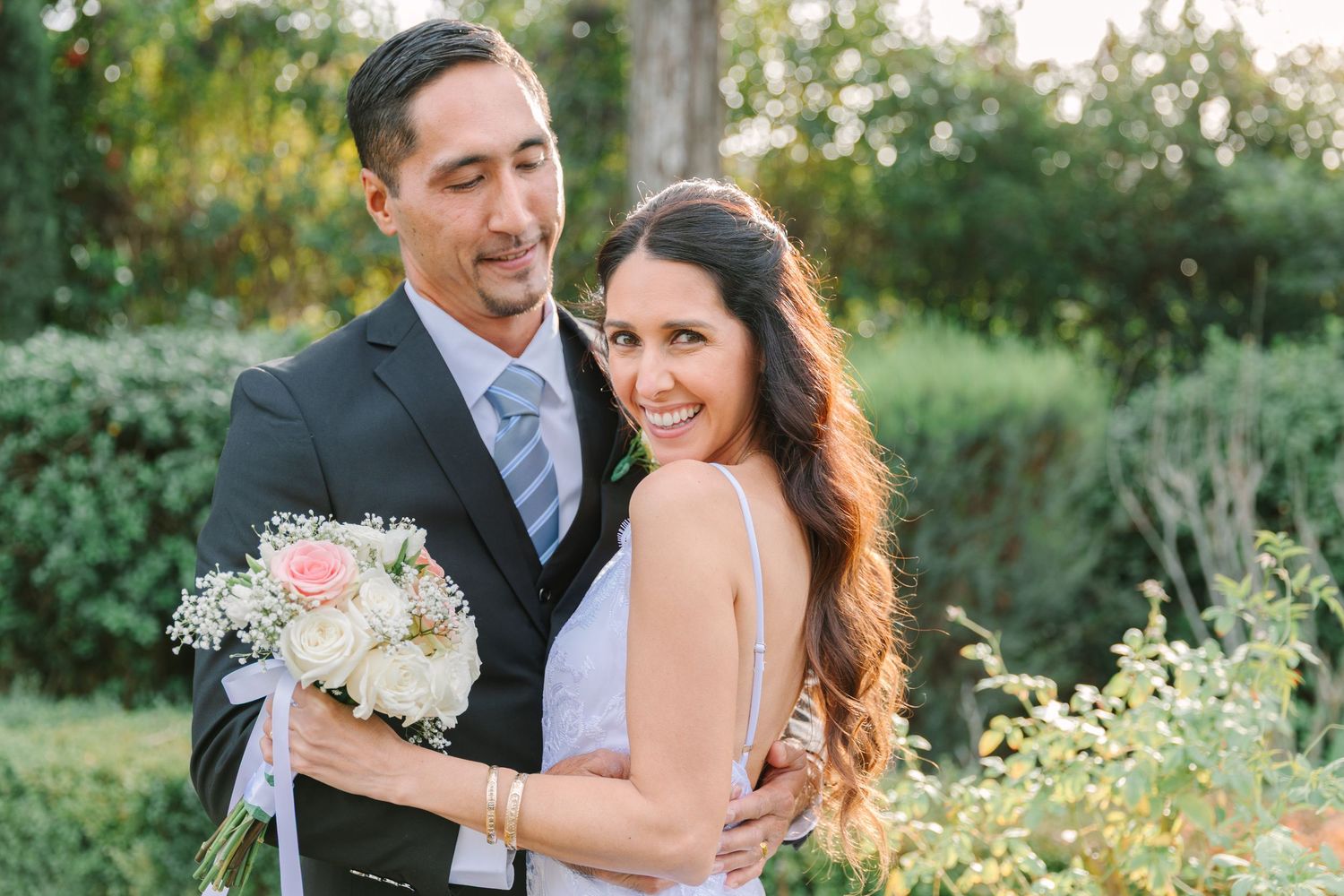A couple shares romantic moments in a garden setting during their wedding photo session at sunset.