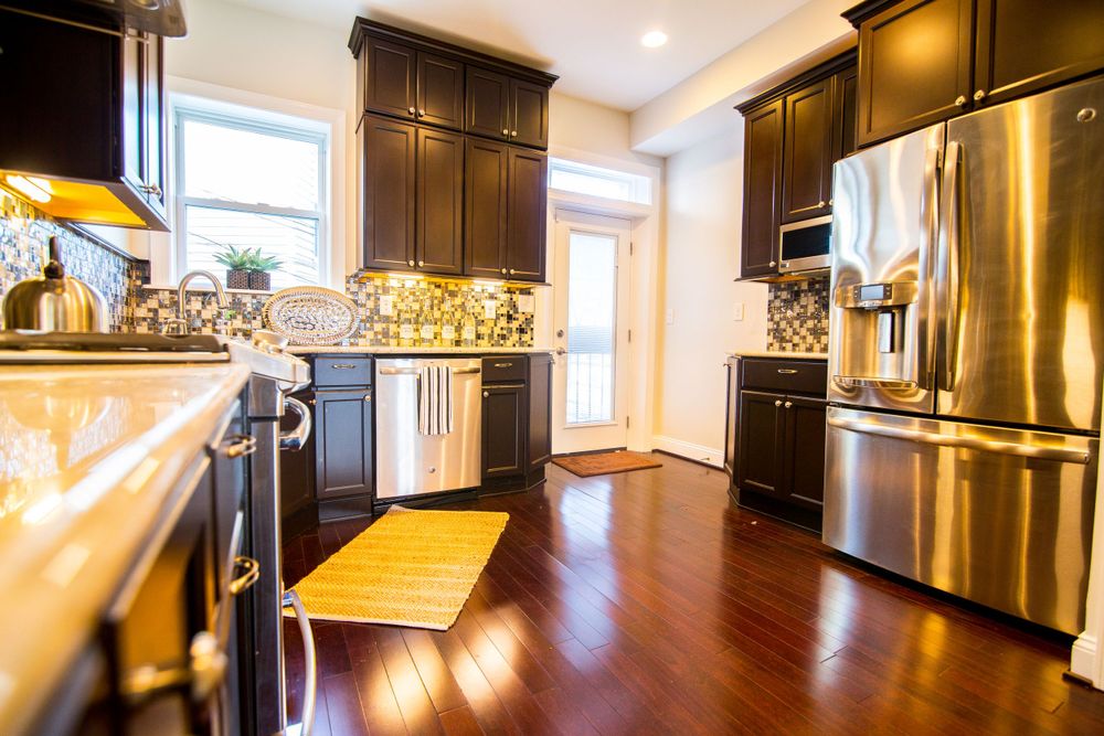Modern kitchen featuring dark wood cabinets, stainless appliances, and wooden floor accents.