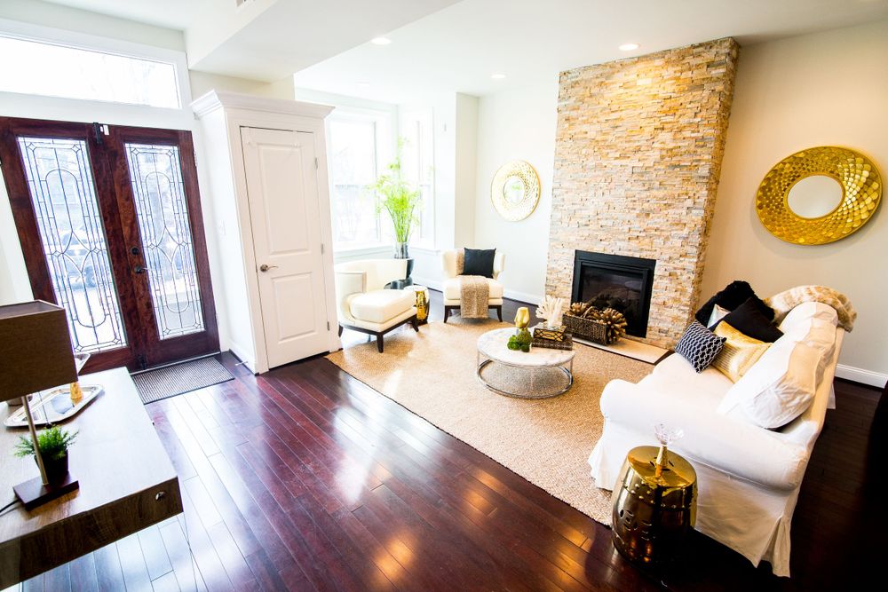 Contemporary living room with stone fireplace, white furniture, and dark hardwood floors.