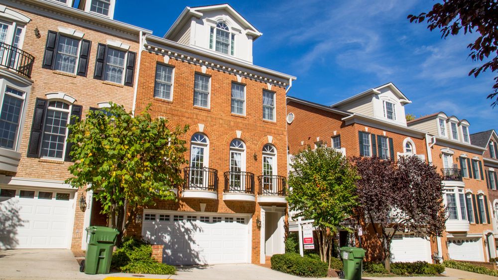 Row of classic brick townhouses with white trim under blue sky.