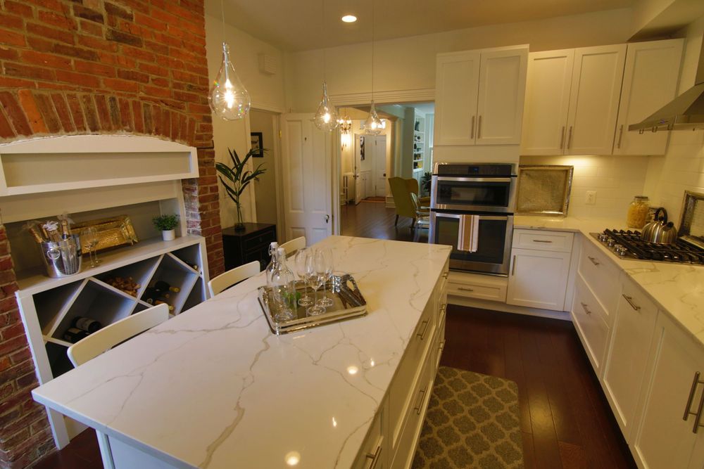 Modern white kitchen with exposed brick wall and large center island.