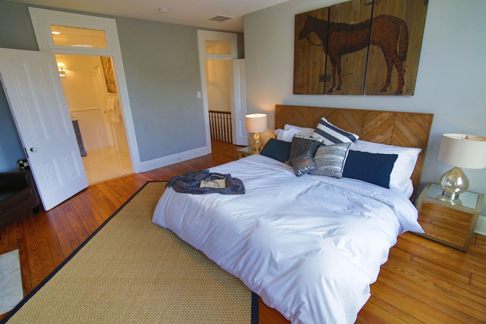 Cozy bedroom with wooden headboard, white bedding and horse artwork.