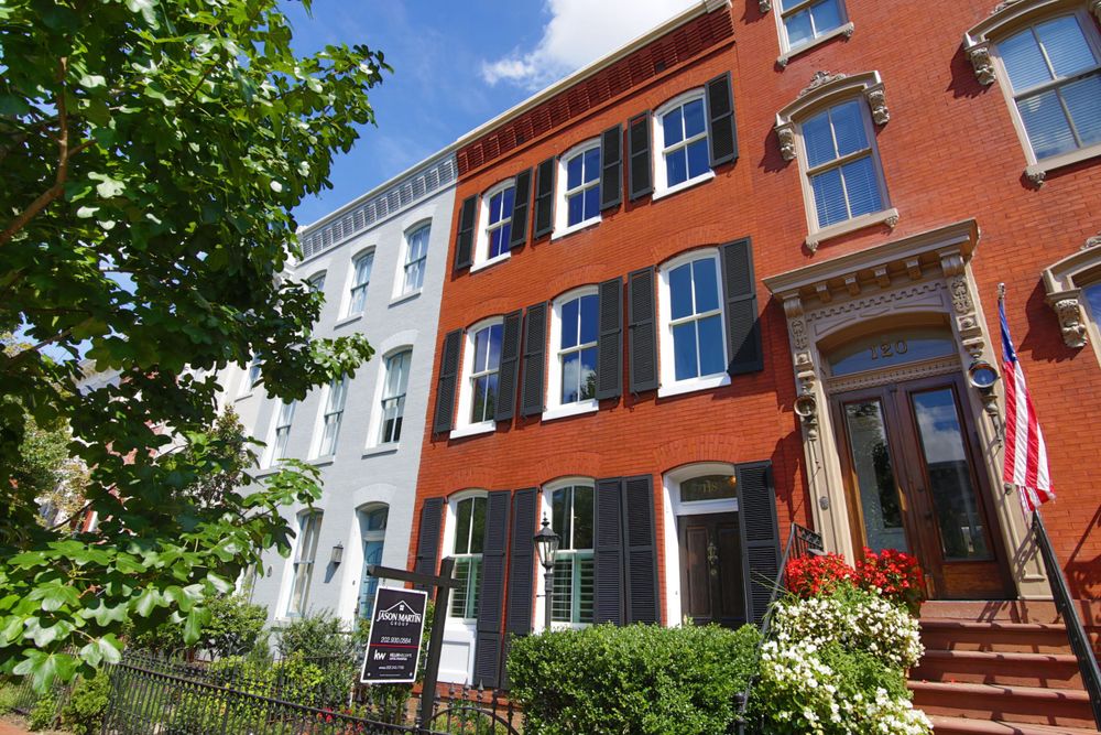 Historic row houses with black shutters and brick facades in urban neighborhood.