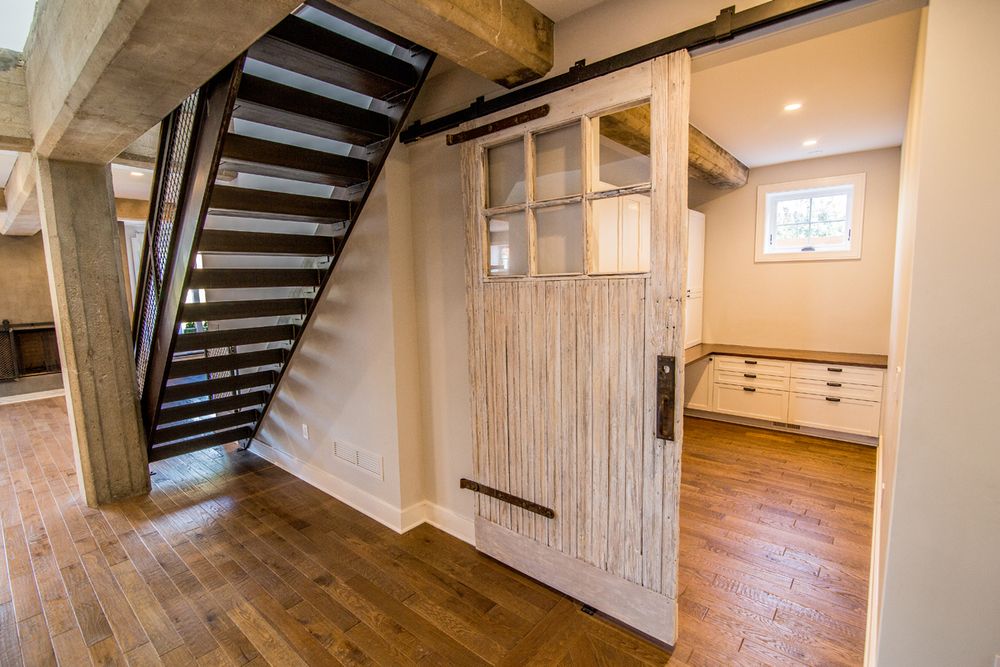 Modern interior with wooden barn door and black metal staircase in rustic style.