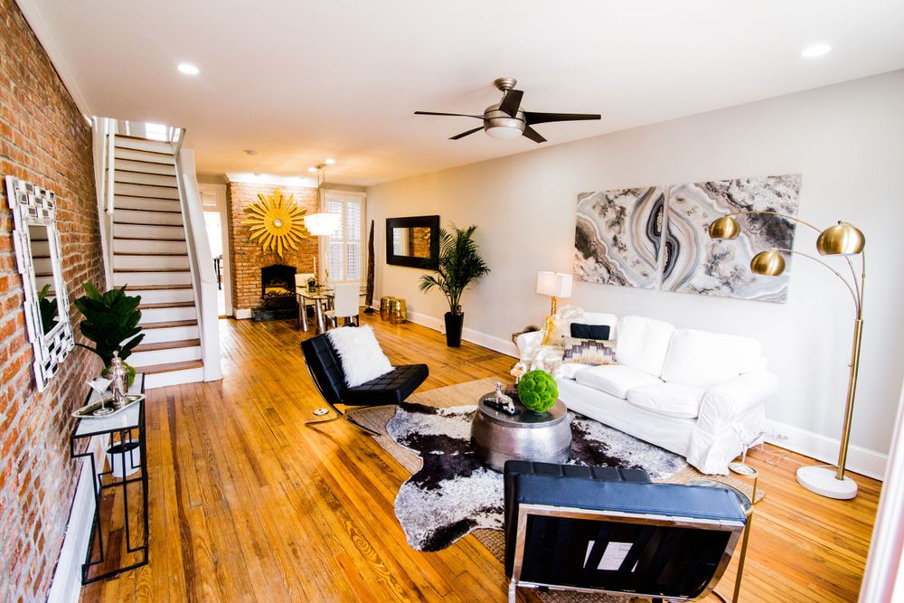 Modern living room with hardwood floors, exposed brick wall, and contemporary black and white furnishings.
