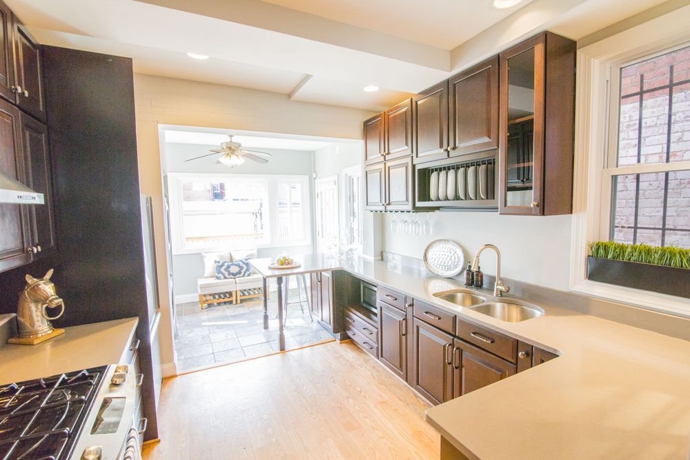 Renovated kitchen with dark wood cabinets, stainless steel appliances, and white countertops.