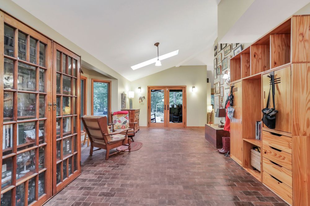Long hallway with built-in wooden storage units and floor-to-ceiling glass-front cabinets.
