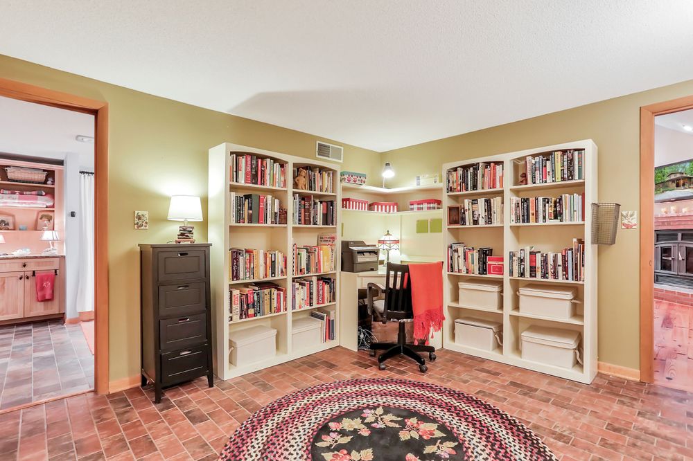 Home library room with wall-to-wall bookshelves, area rug, and desk space.
