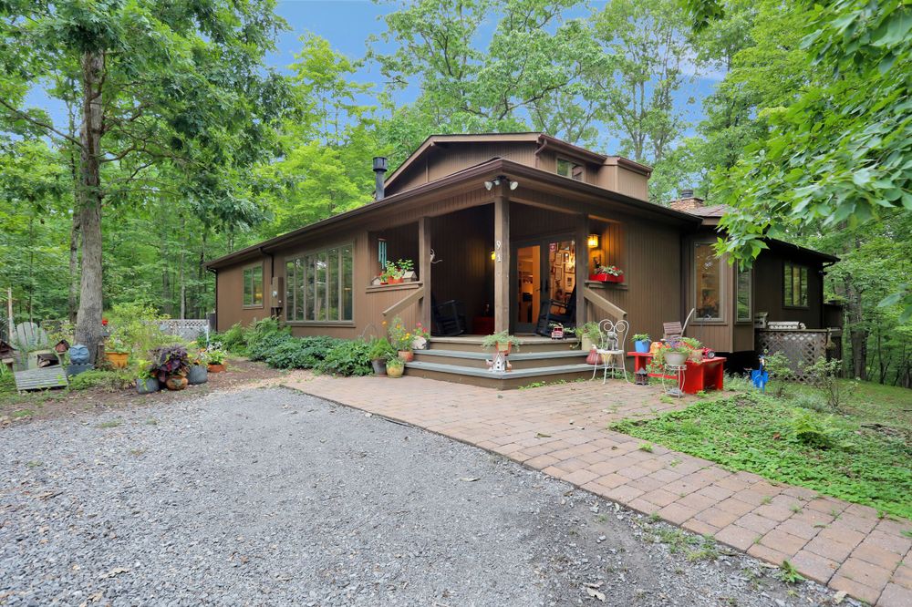 Modern brown cabin exterior with covered entry porch and landscaped walkway.