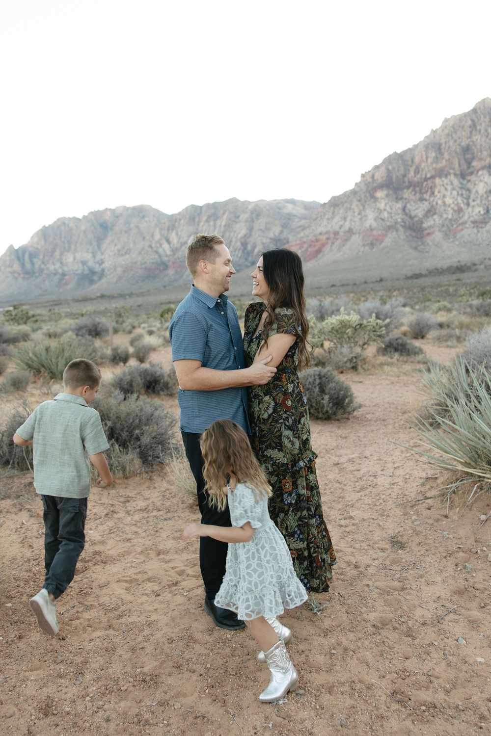 A family shares tender moments together against a desert mountain backdrop during a photo session.