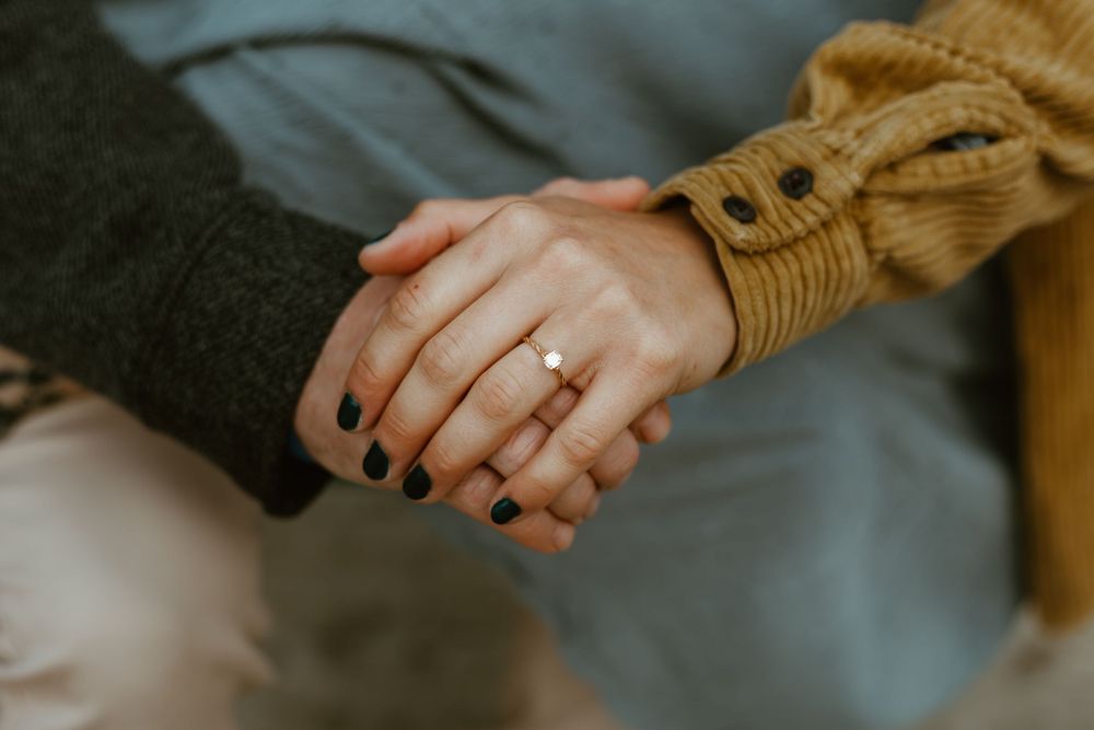 Close-up of hands clasped together showing an engagement ring.