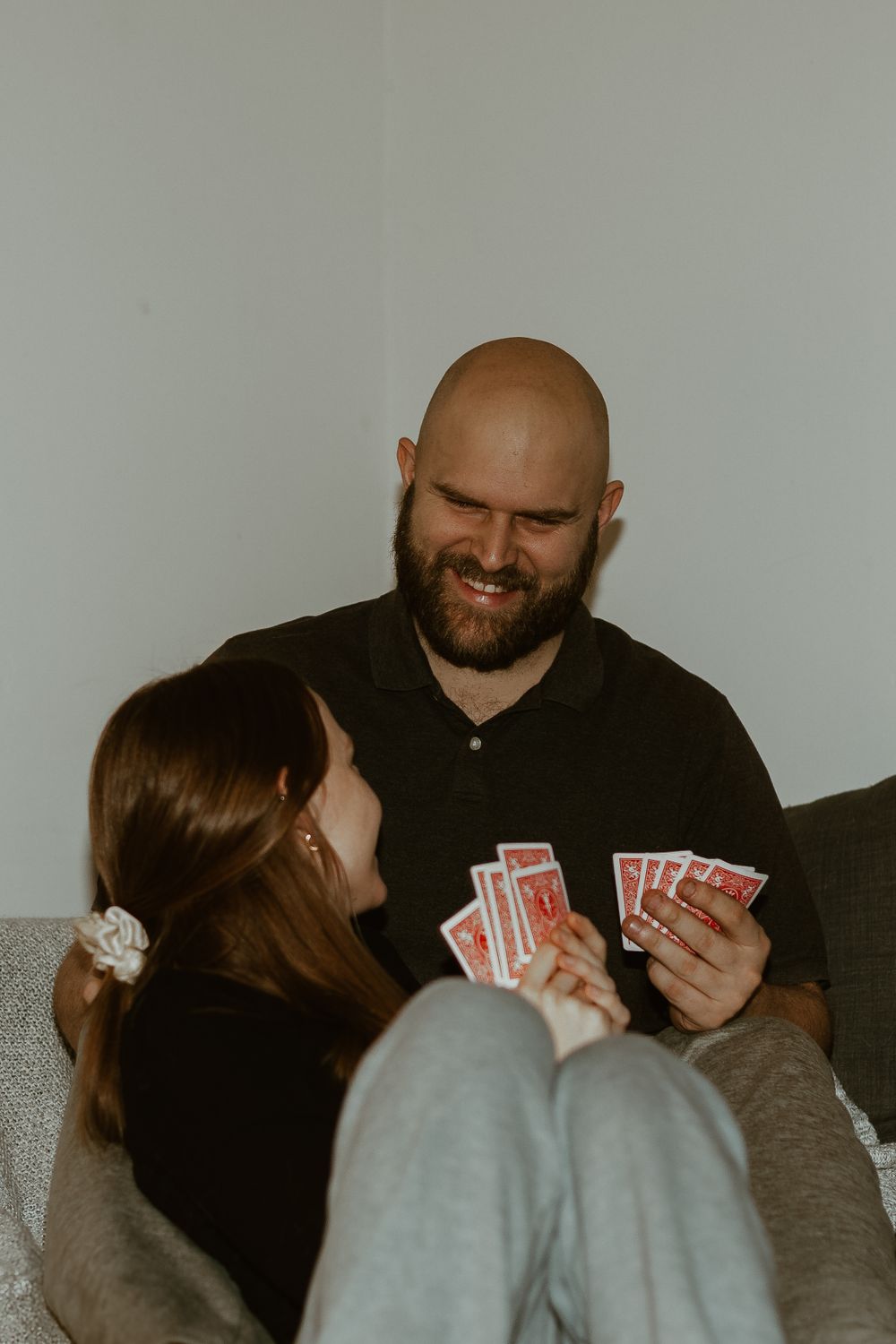 A couple shares a playful moment while playing card games on a comfortable couch.