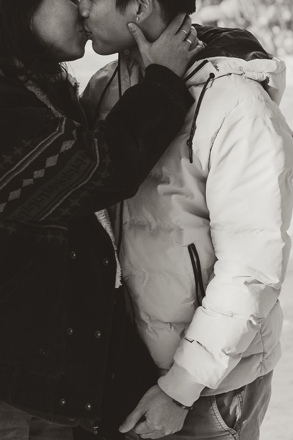 Intimate black and white portrait of couple embracing in winter outerwear.