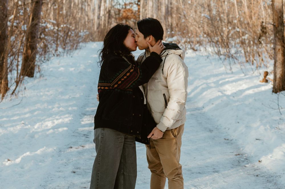 Romantic winter scene with couple sharing intimate moment on snowy path.