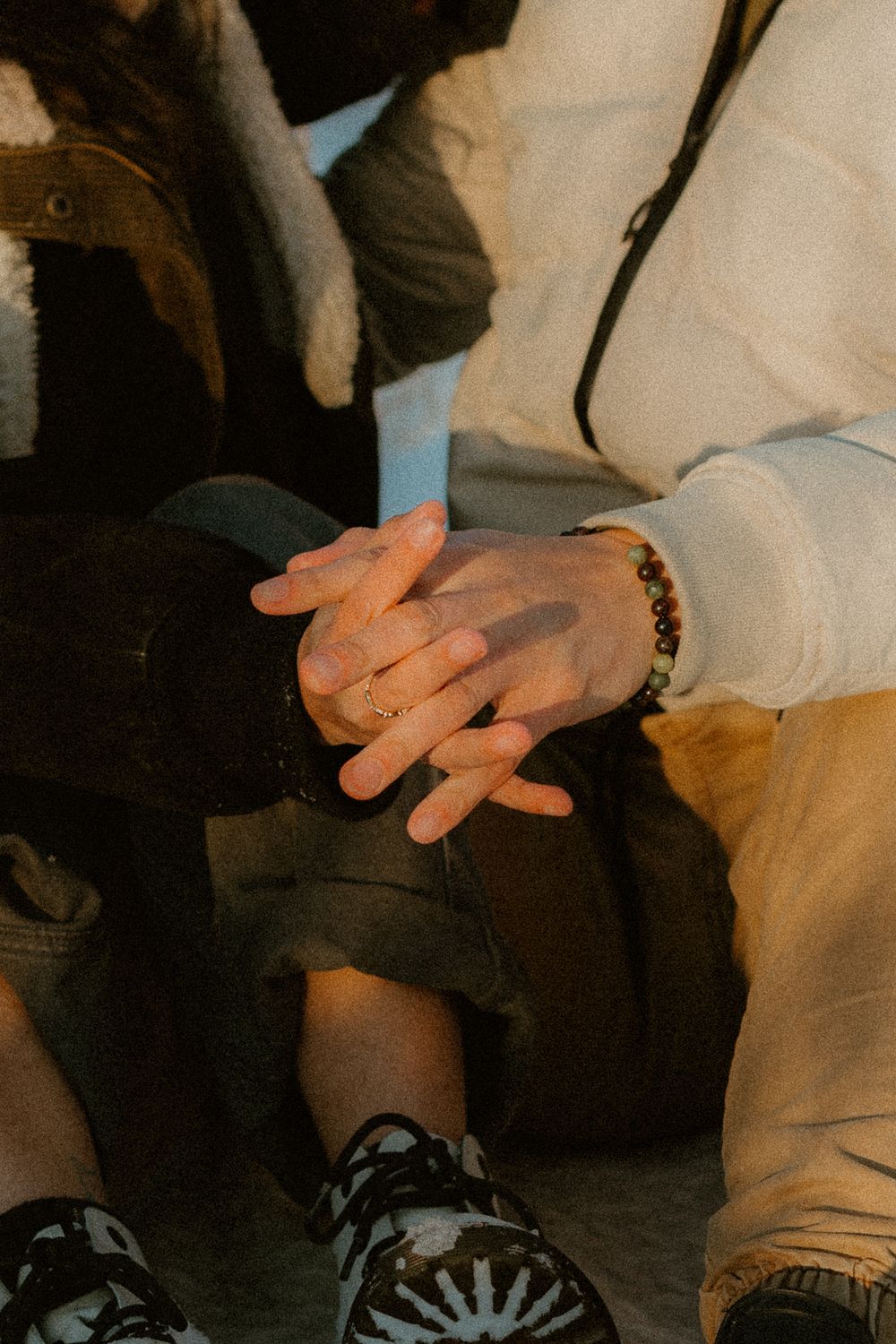 Close-up of intertwined hands resting together during winter photoshoot.