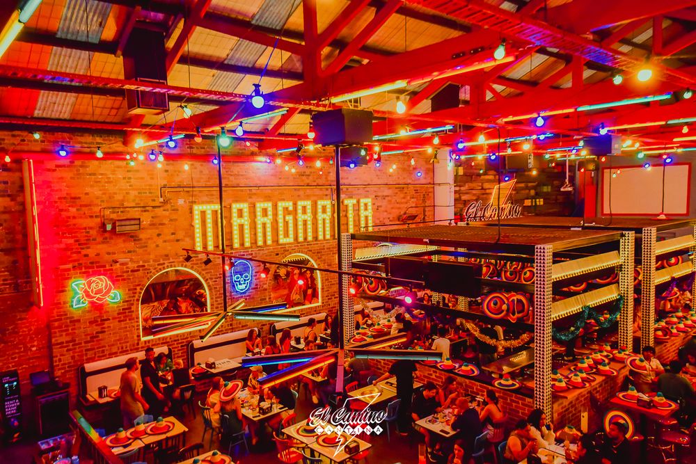 Vibrant red-lit bar interior with neon signs and Margarita signage.