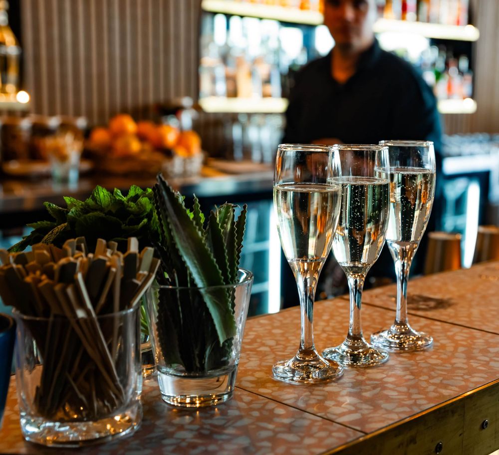 Elegant champagne flutes and decorative plants arranged on bar counter.