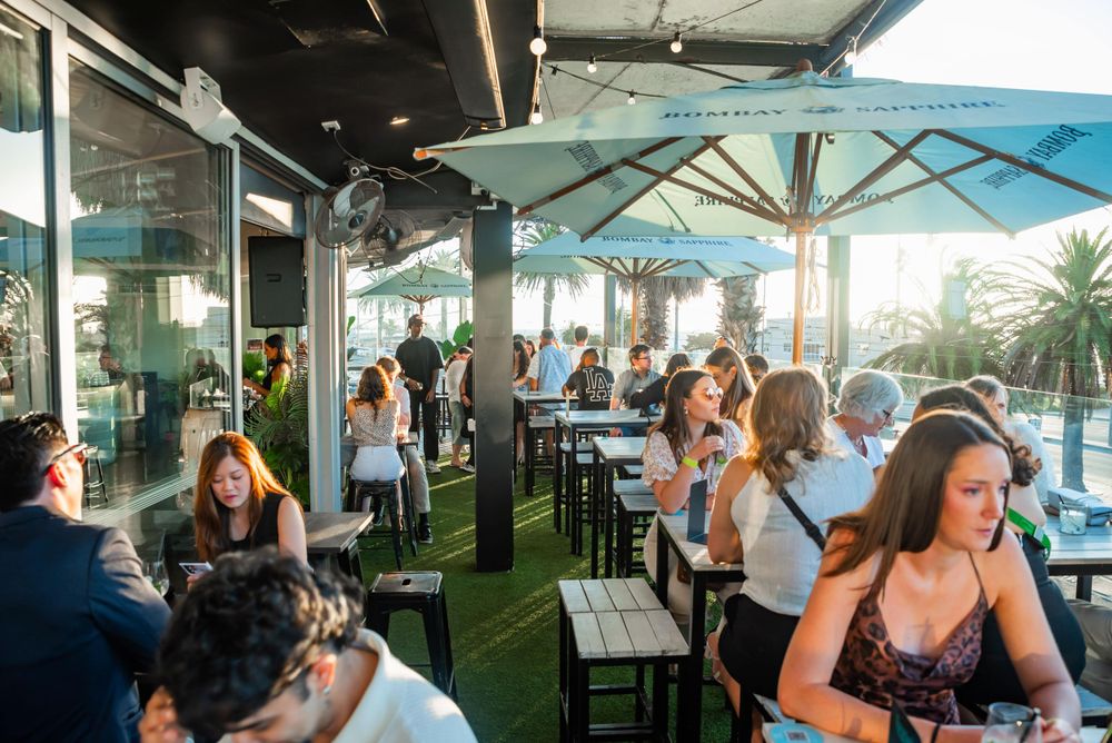 Outdoor rooftop bar patio with umbrella seating and ocean views.