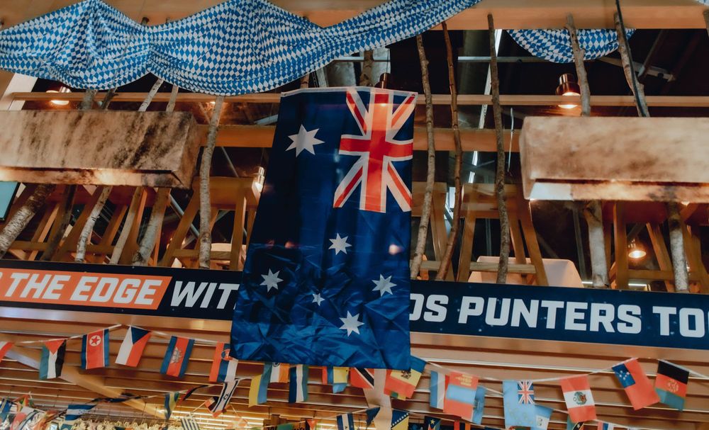 Australian flag hangs from ceiling with blue and white checkered decorations in a beer hall.