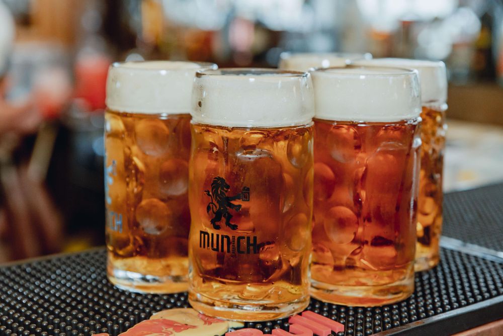 Three large beer steins filled with golden lager on a bar counter.