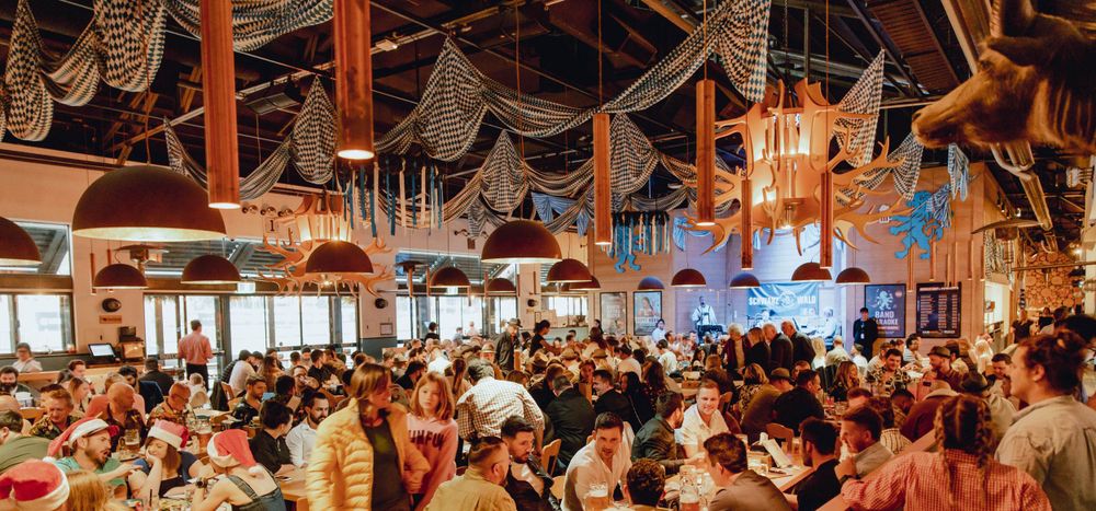 Packed beer hall interior with festive decorations and string lights creating a lively atmosphere.
