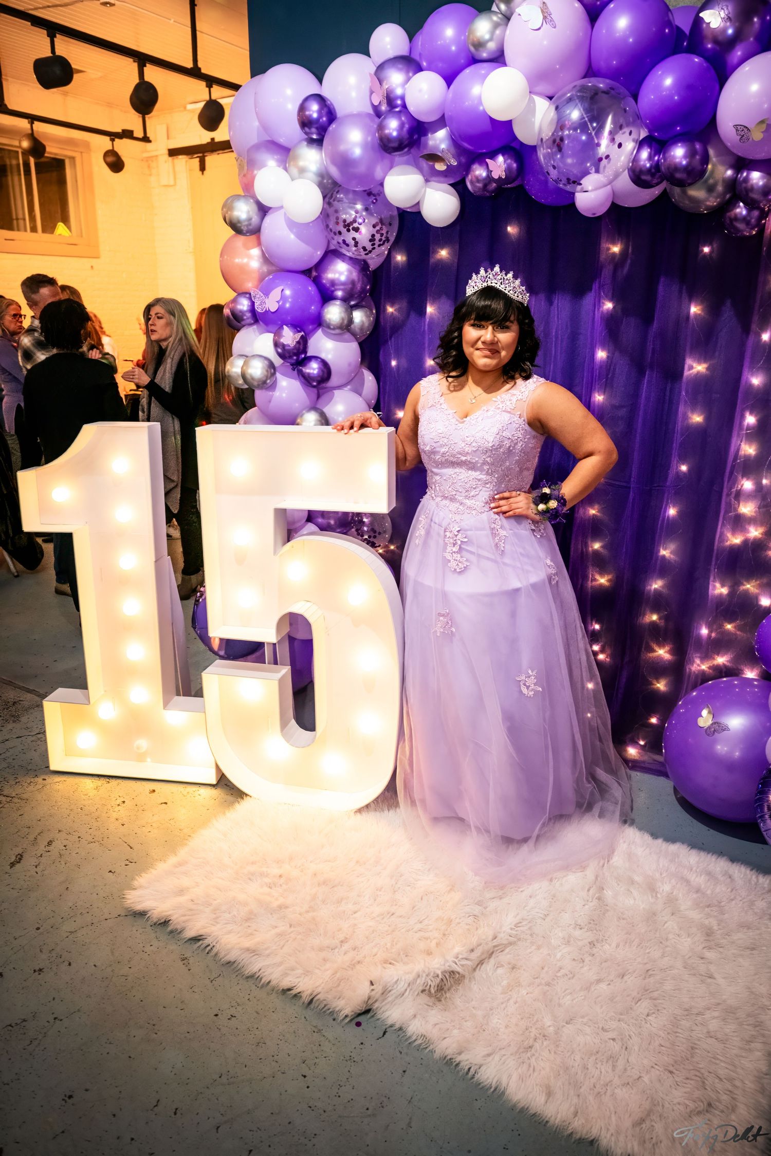 A quinceañera celebration featuring a light-up number 15 and purple balloon arch decoration.