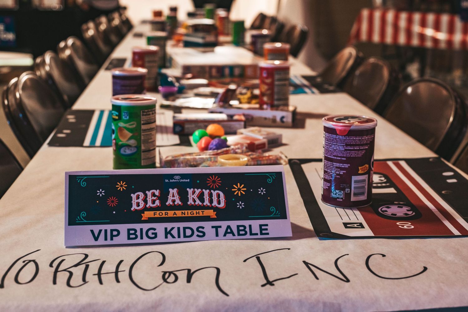 A collection of board games and activities laid out on tables at a party or event with signs and decorations.