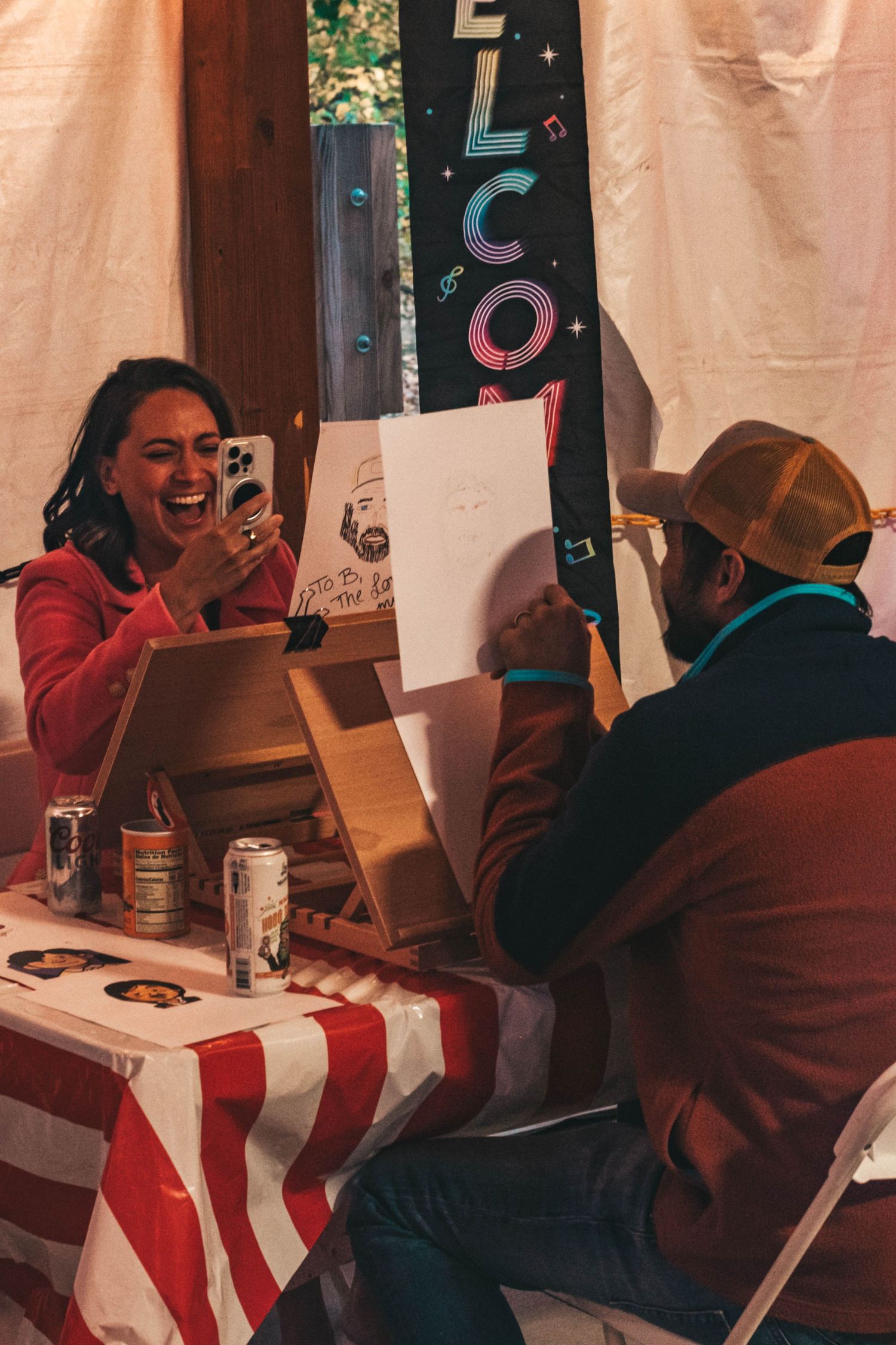 Person sitting at a table laughing while looking at their phone during a casual gathering.