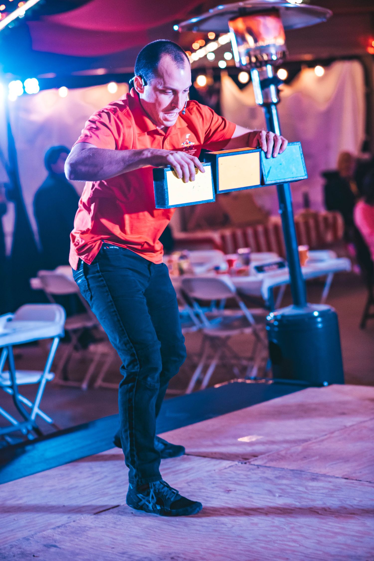 Person in red clothing performing dance moves on a stage under blue and purple lighting.