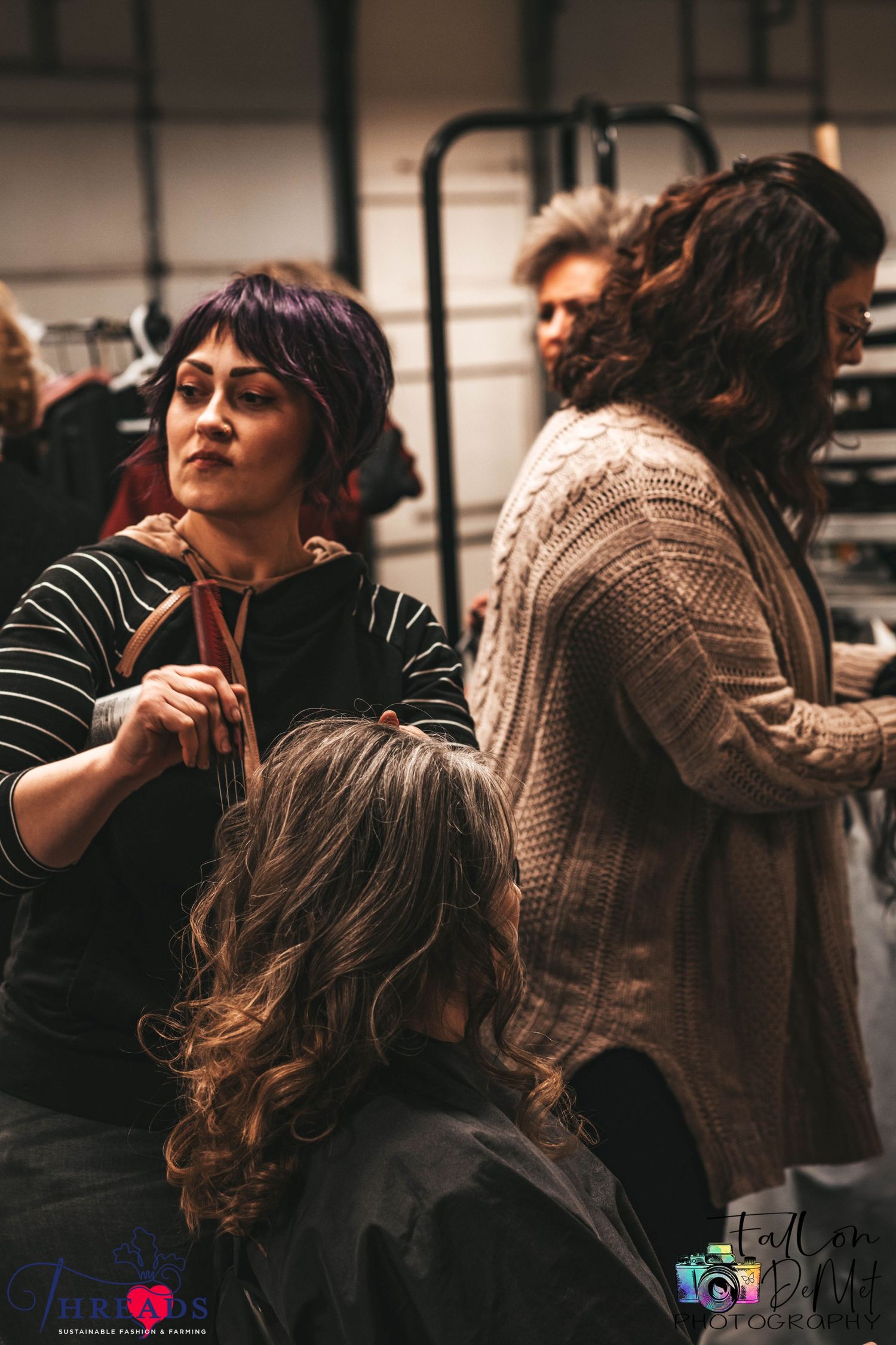 Hair styling professionals working on models backstage at a fashion event.