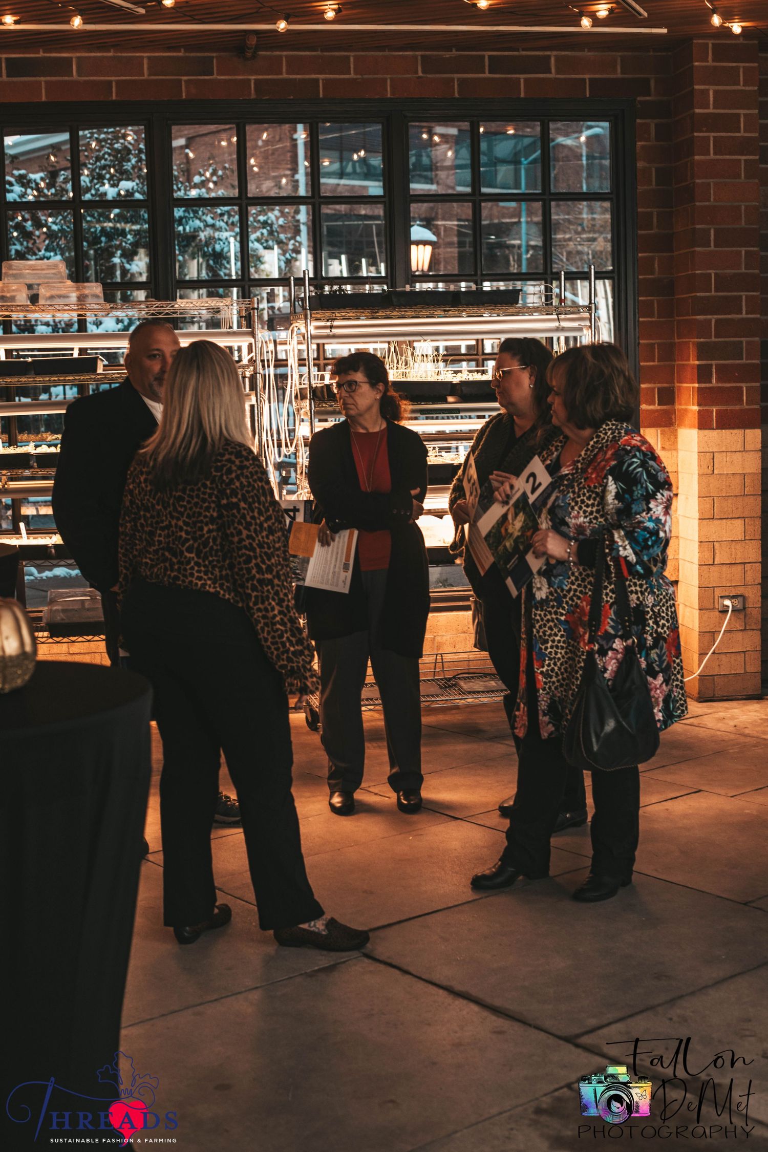 Group of people gathered in conversation at an indoor venue with atmospheric lighting.
