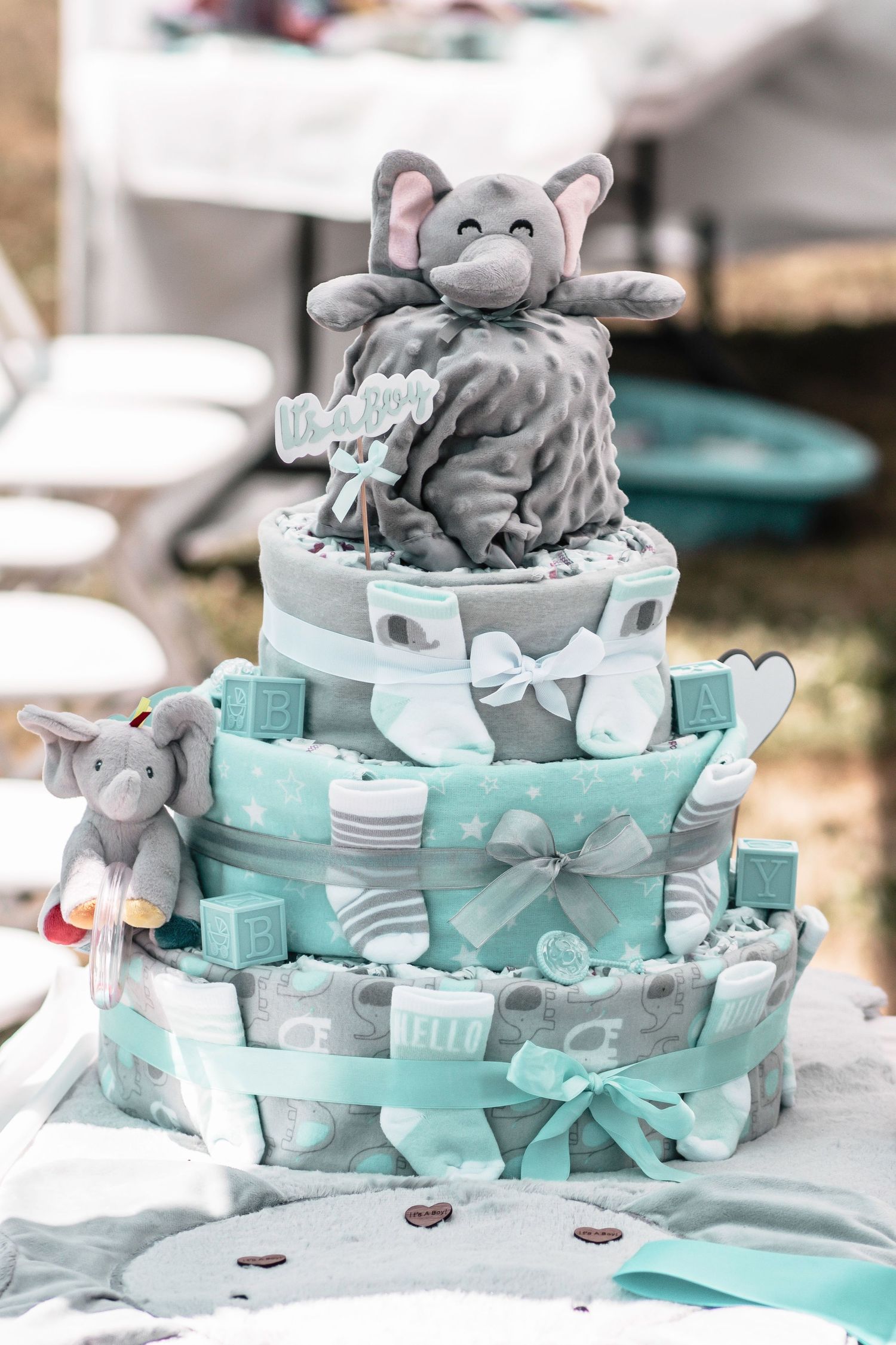 Tiered diaper cake decorated with gray elephant plush toys and mint green ribbons.