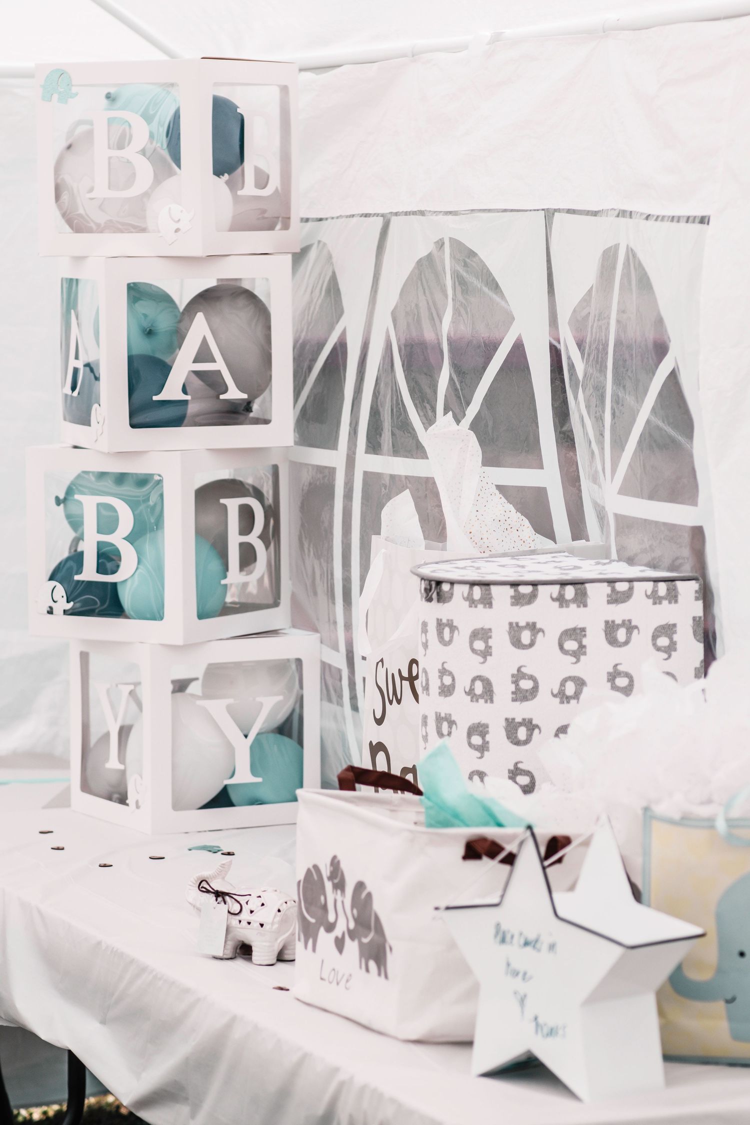 Baby shower decorations with white and turquoise alphabet blocks and star accents.
