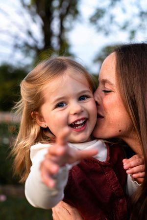 Sweet moment captured between child and parent sharing affection outdoors.