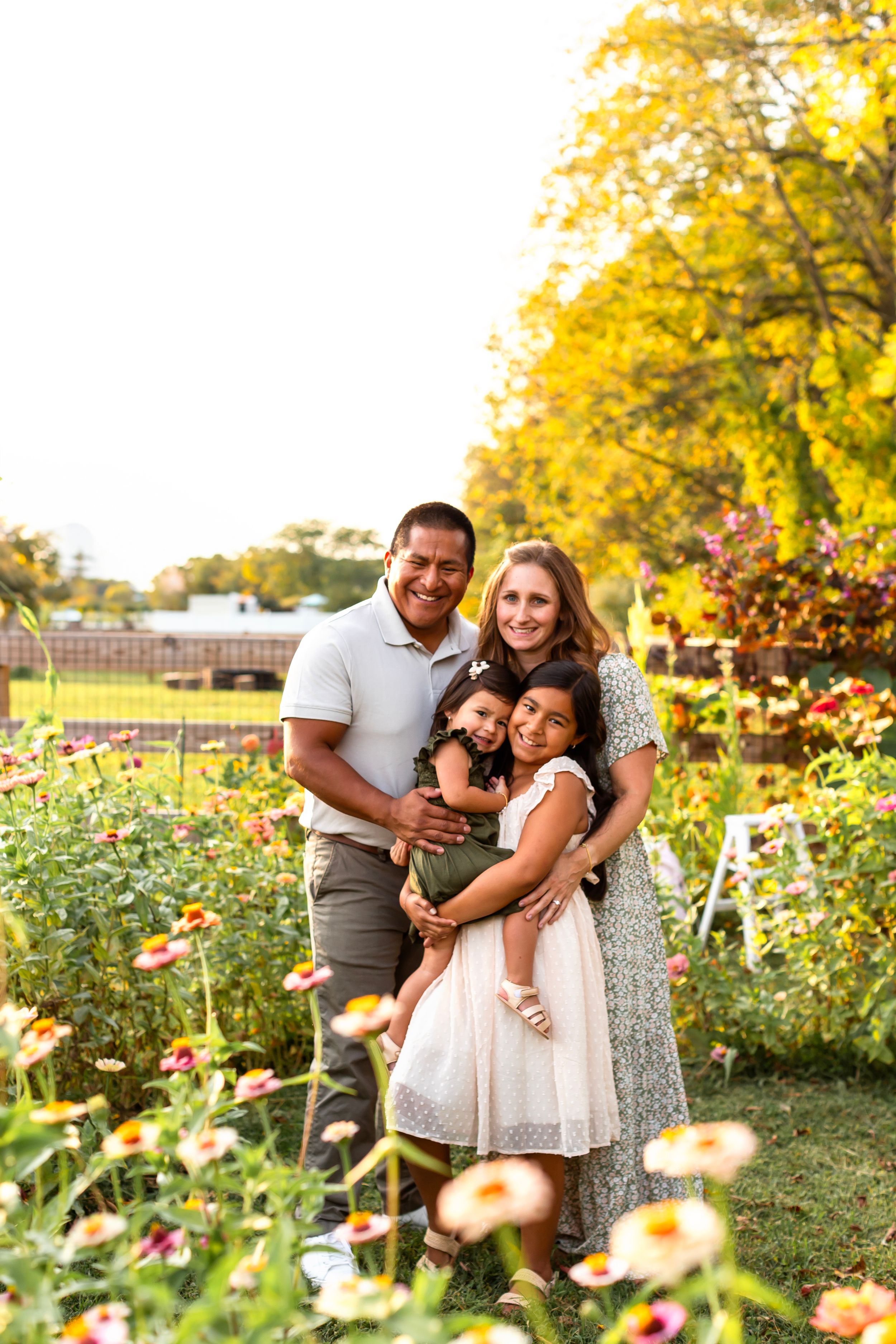 Family portrait in colorful garden setting with yellow trees and wildflowers.
