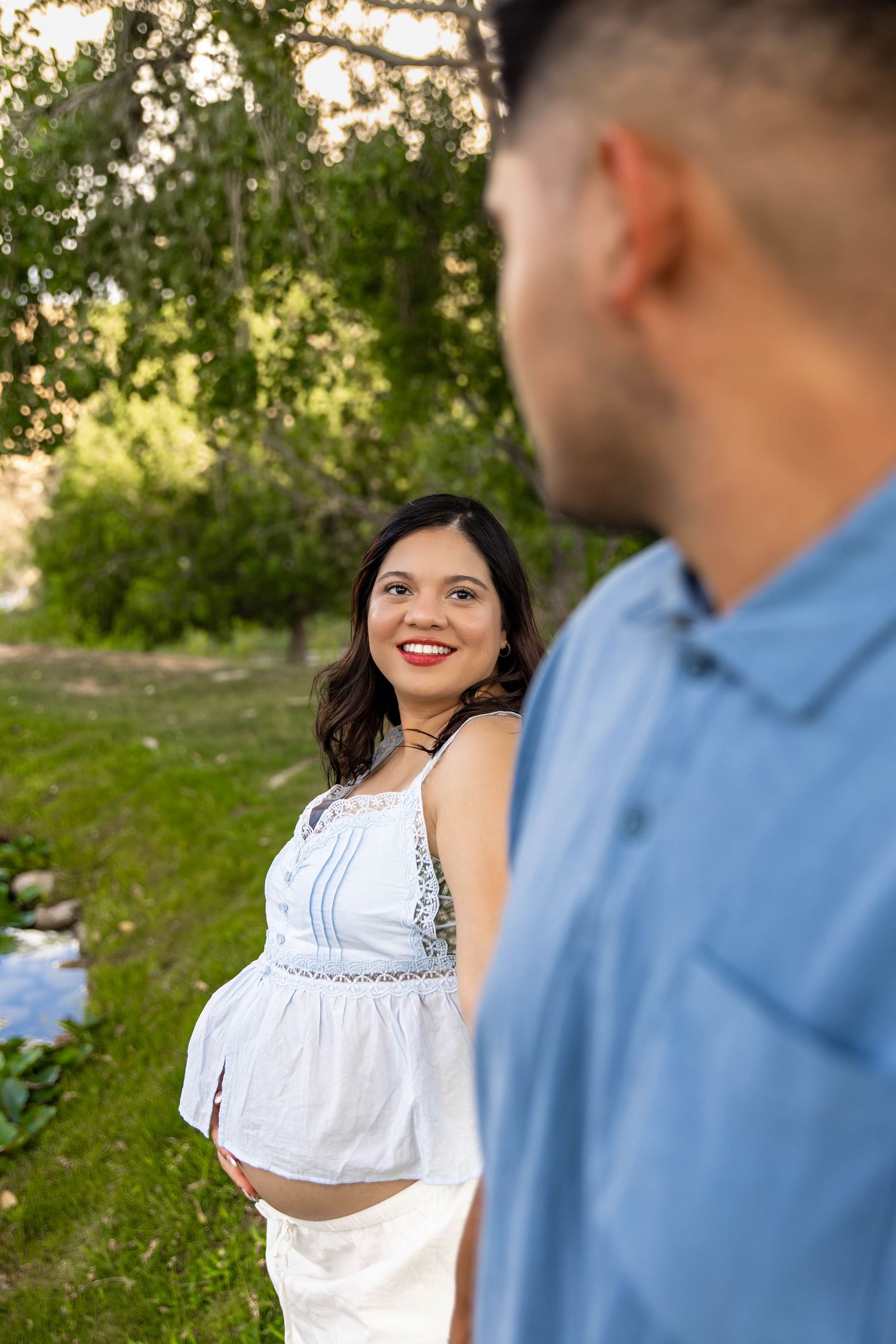 Expectant couple shares a tender moment outdoors during a maternity photoshoot at sunset.