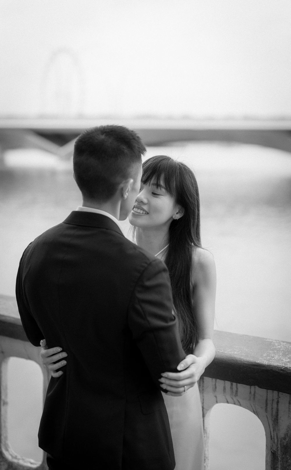 Newlyweds share an intimate moment by a stone wall and garden during their wedding photoshoot.