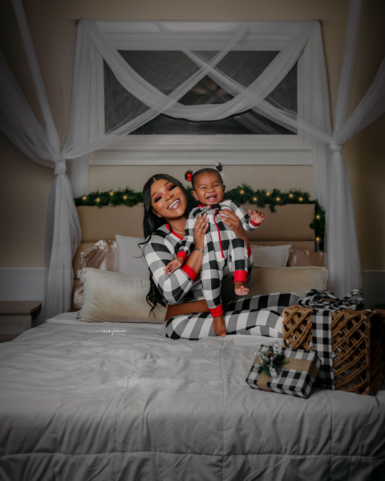 Playful holiday bedroom photoshoot with people wearing coordinating buffalo plaid outfits on white bedding.